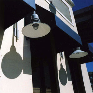 Two blue outdoor lamps and their reflection into the white wall behind them